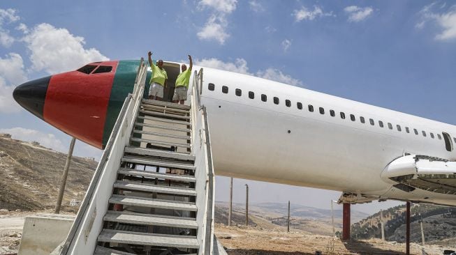 Saudara kembar Palestina Atallah dan Khamis al-Sairafi (60) berdiri bersama di pesawat Boeing 707 yang diubah menjadi restoran yang mereka sebut "Restoran Maskapai Penerbangan Palestina-Yordania dan Kedai Kopi Al-Sairafi Nablus", di Kota Nablus, Palestina, pada (5/7/2021). [JAAFAR ASHTIYEH / AFP]