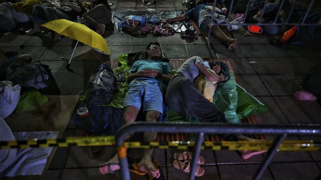 Warga tertidur saat mereka mengantre semalaman untuk swab test COVID-19 gratis di Wat Phra Sri Mahathat Woramahawihan, Bangkok, pada (9/7/2021) dini hari. [Lillian SUWANRUMPHA / AFP]