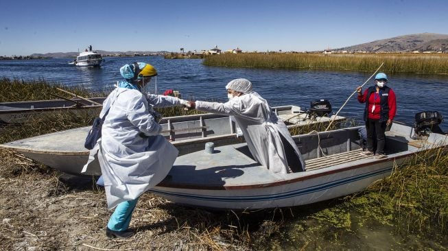 Petugas kesehatan tiba di Pulau Uros untuk menyuntik warga dengan vaksin COVID-19 Sinopharm di Danau Titicaca, Puno, Peru, pada (7/7/2021). [Carlos MAMANI / AFP]