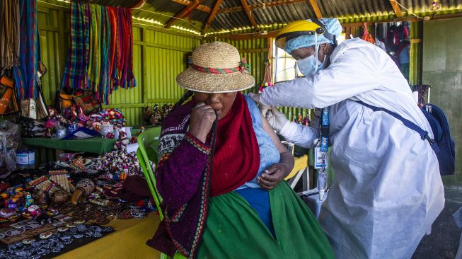 Petugas kesehatan menyuntik warga dengan vaksin COVID-19 Sinopharm di Pulau Uros, Danau Titicaca, Puno, Peru, pada (7/7/2021). [Carlos MAMANI / AFP]