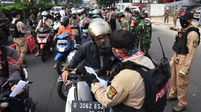 Pengendara menunjukkan Surat Tanda Registrasi Pekerja (STRP) kepada petugas di pos penyekatan pembatasan mobilitas masyarakat pada PPKM Darurat di wilayah perbatasan menuju Jakarta di Jalan Margonda, Depok, Jawa Barat, Jumat (9/7/2021). ANTARA FOTO/Indrianto Eko Suwarso