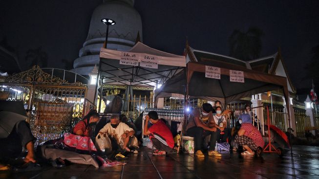 Warga berkerumun di bawah tenda saat mengantre semalaman untuk swab test COVID-19 gratis di Wat Phra Sri Mahathat Woramahawihan, Bangkok, pada (9/7/2021) dini hari. [Lillian SUWANRUMPHA / AFP]