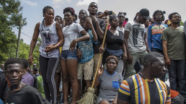 Kerumunan mengelilingi kantor Polisi Petionville di mana orang-orang bersenjata, yang dituduh terlibat dalam pembunuhan Presiden Jovenel Moise, ditahan di Port au Prince, Haiti, pada (8/7/2021). [Valerie Baeriswyl / AFP]