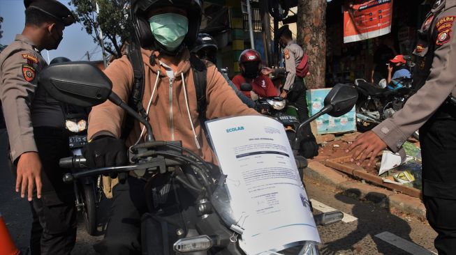 Pengendara menempel Surat Tanda Registrasi Pekerja (STRP) di bagian depan motornya saat melintasi pos penyekatan pembatasan mobilitas masyarakat pada PPKM Darurat di wilayah perbatasan menuju Jakarta di Jalan Raya Lenteng Agung, Jakarta, Jumat (9/7/2021). ANTARA FOTO/Indrianto Eko Suwarso
