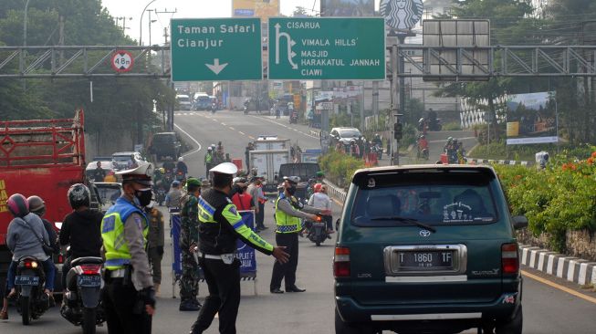 Anggota Satlantas Polres Bogor mengarahkan pengendara mobil untuk berputar arah saat penyekatan jalur Puncak di Simpang Gadog, Kabupaten Bogor, Jawa Barat, Sabtu (10/7/2021).  ANTARA FOTO/Arif Firmansyah