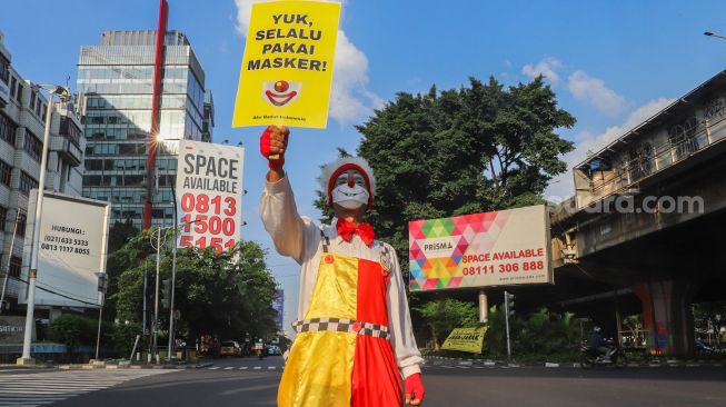 Angggota Komunitas Aku Badut Indonesia (ABI) melakukan aksi kampanye untuk menggunakan masker di kawasan Cilandak, Jakarta Selatan, Senin (12/7/2021). [Suara.com/Alfian Winanto]