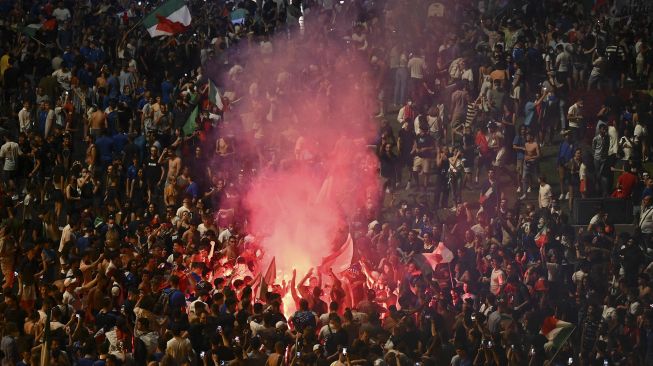 Pendukung tim sepak bola nasional Italia merayakan kemenangan setelah Italia mengalahkan Inggris pada final UEFA EURO 2020 di Roma, pada (11/7/2021). [Vincenzo PINTO / AFP]