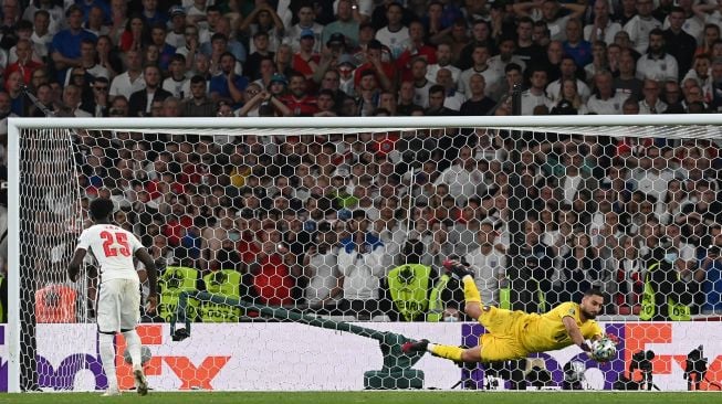 Gelandang Inggris Bukayo Saka gagal mencetak gol melewati kiper Italia Gianluigi Donnarumma dalam adu penalti selama pertandingan sepak bola final EURO 2020 antara Italia melawan Inggris Stadion Wembley, London, Senin (12/7) dini hari WIB.  Paul ELLIS / AFP