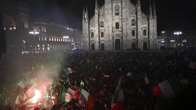 Pendukung tim sepak bola nasional Italia merayakan kemenangan setelah Italia mengalahkan Inggris pada final UEFA EURO 2020 di Piazza del Duomo, Milan pada (11/7/2021). [Marco BERTORELLO / AFP]