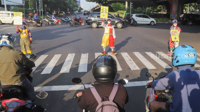 Angggota Komunitas Aku Badut Indonesia (ABI) melakukan aksi kampanye untuk menggunakan masker di kawasan Cilandak, Jakarta Selatan, Senin (12/7/2021). [Suara.com/Alfian Winanto]