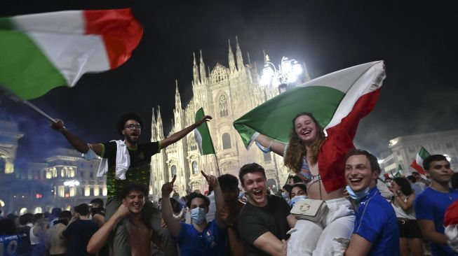 Pendukung tim sepak bola nasional Italia merayakan kemenangan setelah Italia mengalahkan Inggris pada final UEFA EURO 2020 di Piazza del Duomo, Milan pada (11/7/2021). [Marco BERTORELLO / AFP]