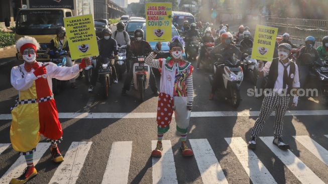 Angggota Komunitas Aku Badut Indonesia (ABI) melakukan aksi kampanye untuk menggunakan masker di kawasan Cilandak, Jakarta Selatan, Senin (12/7/2021). [Suara.com/Alfian Winanto]