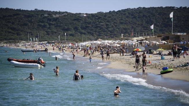 Orang-orang mengunjungi pantai Pampelonne setelah Prancis baru-baru ini melonggarkan tindakan pencegahan penyebaran COVID-19 di Ramatuelle, Saint-Tropez, Prancis, pada (10/7/2021). [CLEMENT MAHOUDEAU / AFP]