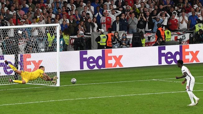 Gelandang Inggris Bukayo Saka gagal mencetak gol melewati kiper Italia Gianluigi Donnarumma (kiri) dalam adu penalti selama pertandingan sepak bola final EURO 2020 antara Italia melawan Inggris Stadion Wembley, London, Senin (12/7) dini hari WIB.  Paul ELLIS / AFP