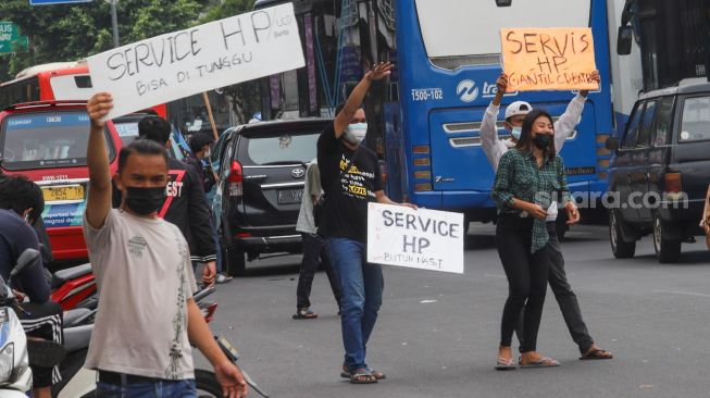 Sejumlah penyedia jasa servis handphone menawarkan jasanya di Kawasan Pusat Grosir Cililitan (PGC), Jakarta Timur, Selasa (13/7/2021). [Suara.com/Alfian Winanto]