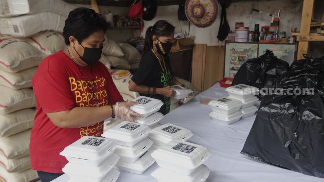 Sukarelawan menyiapkan makanan di dapur umum peduli COVID-19 di Karet Semanggi, Setiabudi, Jakarta, Selasa (13/7/2021). [Suara.com/Angga Budhiyanto]