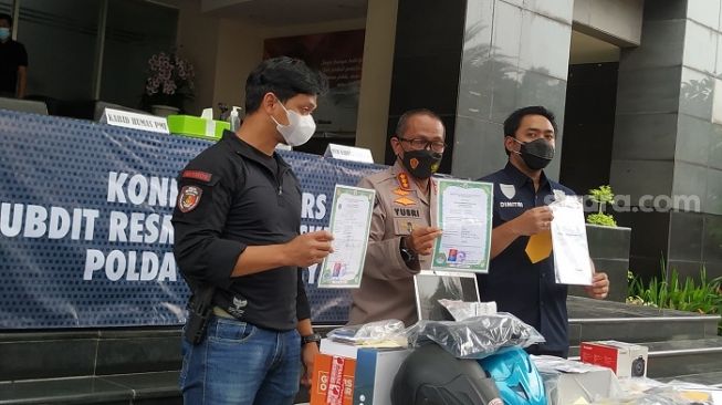 Polisi saat menunjukkan barang bukti hasil PCR positif palsu yang jual selama pandemi Covid-19. (Suara.com/M Yasir)