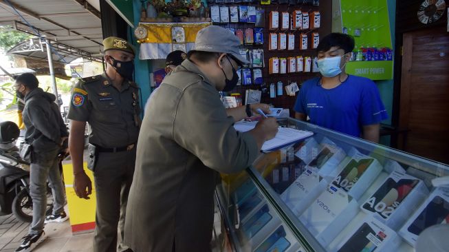 Satpol PP Kota Denpasar menindak tempat usaha non esensial yang masih buka saat Pemberlakuan Pembatasan Kegiatan Masyarakat (PPKM) Darurat di Denpasar, Bali, Selasa (13/7/2021). ANTARA FOTO/Nyoman Hendra Wibowo