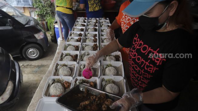 Sukarelawan menyiapkan makanan di dapur umum peduli COVID-19 di Karet Semanggi, Setiabudi, Jakarta, Selasa (13/7/2021). [Suara.com/Angga Budhiyanto]