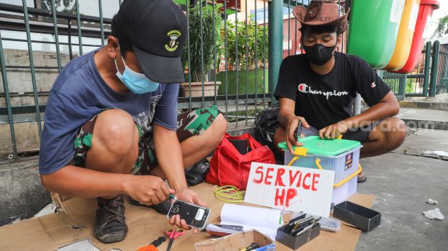 Penyedia jasa servis mereparasi handphone di  Kawasan Pusat Grosir Cililitan (PGC), Jakarta Timur, Selasa (13/7/2021). [Suara.com/Alfian Winanto]