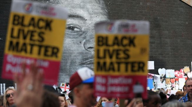 Pengunjuk rasa antirasisme berkumpul di depan mural Marcus Rashford yang menjadi sasaran vandalisme di Manchester, Inggris, pada 13 Juli 2021. [Photo/AFP]
