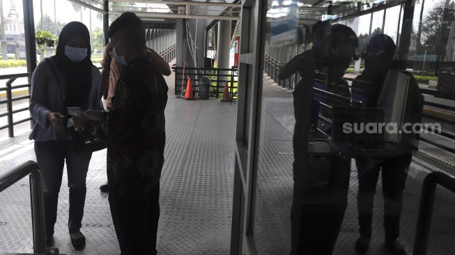 Petugas memeriksa surat tanda registrasi pekerja (STRP) calon penumpang di Halte Transjakarta Gelora Bung Karno, Jakarta, Rabu (14/7/2021). [Suara.com/Angga Budhiyanto]