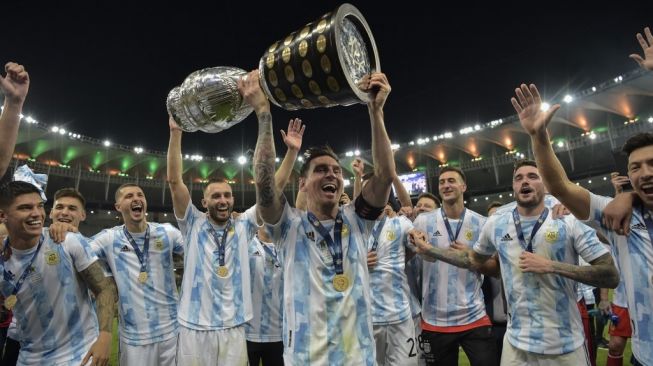 Kapten Timnas Argentina, Lionel Messi (tengah) mengangkat trofi juara Copa America 2021. [CARL DE SOUZA / AFP]