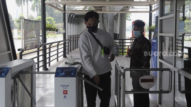 Calon penumpang berjalan di Halte Transjakarta Gelora Bung Karno, Jakarta, Rabu (14/7/2021). [Suara.com/Angga Budhiyanto]