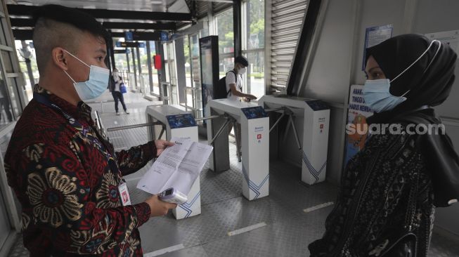 Petugas memeriksa surat tanda registrasi pekerja (STRP) calon penumpang di Halte Transjakarta Gelora Bung Karno, Jakarta, Rabu (14/7/2021). [Suara.com/Angga Budhiyanto]