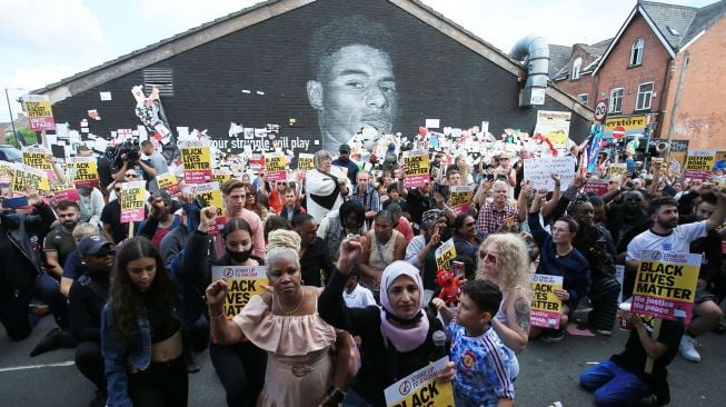 Pengunjuk rasa antirasisme berkumpul di depan mural Marcus Rashford yang menjadi sasaran vandalisme di Manchester, Inggris, pada 13 Juli 2021. [Photo/AFP]