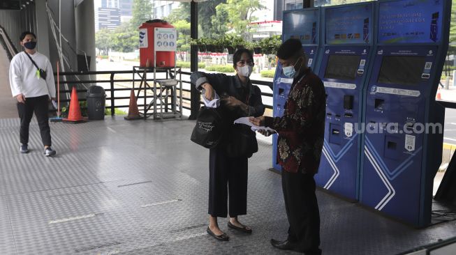 Petugas memeriksa surat tanda registrasi pekerja (STRP) calon penumpang di Halte Transjakarta Gelora Bung Karno, Jakarta, Rabu (14/7/2021). [Suara.com/Angga Budhiyanto]