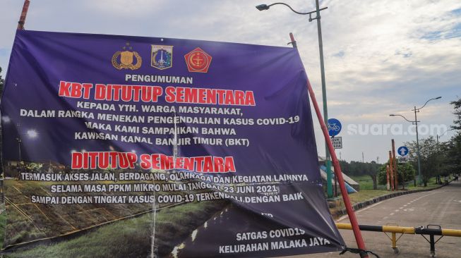 Spanduk berisi penutupan kawasan Banjir Kanal Timur (BKT), Jakarta Timur, Rabu (14/7/2021). [Suara.com/Alfian Winanto]