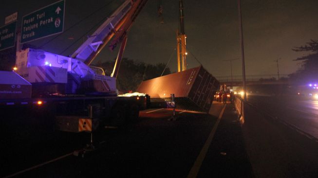 Petugas mengevakuasi truk kontainer yang mengalami kecelakaan di Tol Satelit arah Dupak, Surabaya, Jawa Timur, Rabu (14/7/2021).  ANTARA FOTO/Didik Suhartono