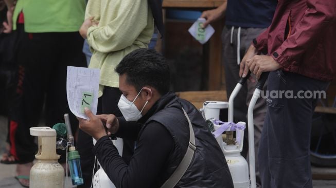 Sejumlah warga mengantre untuk mengisi ulang oksigen medis yang dibagikan secara gratis di kawasan Manggarai, Jakarta, Kamis (15/7/2021). [Suara.com/Angga Budhiyanto]