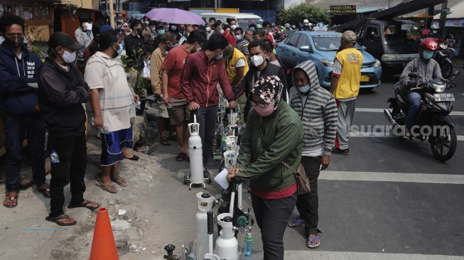 Sejumlah warga mengantre untuk mengisi ulang oksigen medis yang dibagikan secara gratis di kawasan Manggarai, Jakarta, Kamis (15/7/2021). [Suara.com/Angga Budhiyanto]