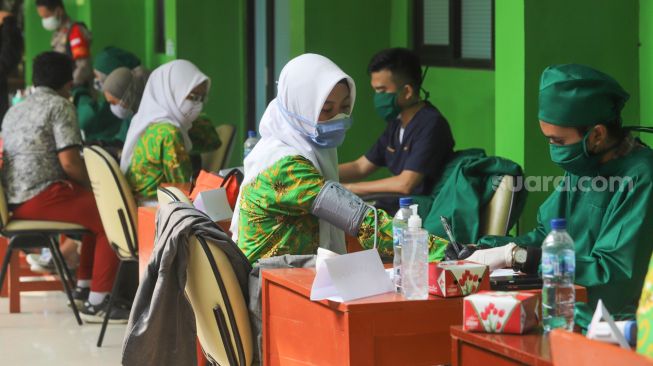 Para pelajar melakukan proses pengecekan kesehatan untuk menjalani vaksinasi Covid-19 di SMA Negeri 38, Jakarta Selatan, Kamis (15/7/2021). [Suara.com/Alfian Winanto]