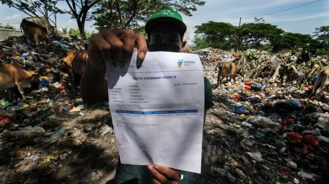 Seorang pemulung menunjukkan surat vaksin COVID-19 di komplek Tempat Pembuangan Akhir (TPA) Alue Lim, Lhokseumawe, Aceh, Rabu (14/7/2021).  ANTARA FOTO/Rahmad