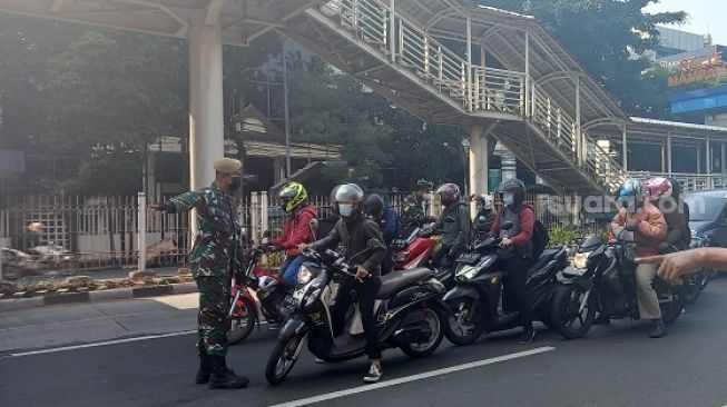 Aparat saat melakukan penjagaan dan pemeriksaan kendaraan di pos penyekatan Mampang Prapanca Raya, Jakarta Selatan. (Suara.com/Arga)