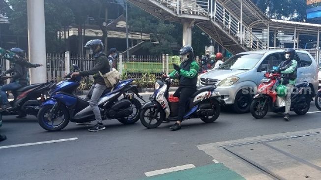 Para pengendara termasuk sopir ojol saat melintas di pos penyekatan di Mampang Prapanca Raya. (Suara.com/Arga)