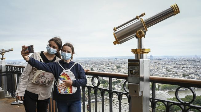 Pengunjung berswafoto dari lantai dua Menara Eiffel di Paris, Prancis, pada (16/7/2021). [Bertrand GUAY / AFP]