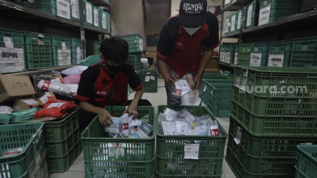 Pekerja menyortir paket obat COVID-19 di gerai ekspedisi pengiriman barang SiCepat di Jalan K.S Tubun, Petamburan, Jakarta, Sabtu (17/7/2021). [Suara.com/Angga Budhiyanto]