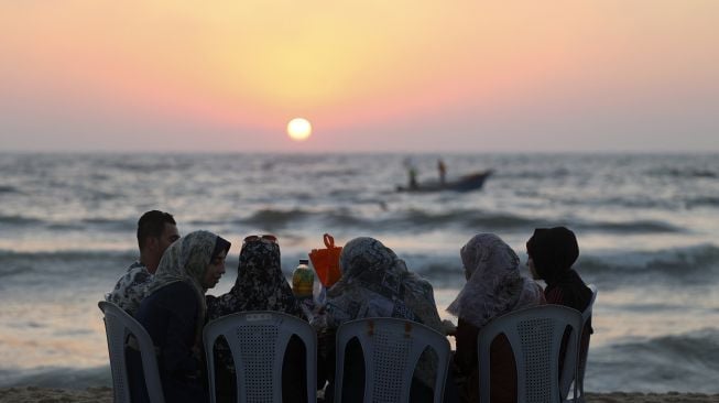 Warga menghabiskan waktu di pantai saat musim panas yang tinggi di Gaza, Palestina, pada (16/7/2021). [MOHAMMED ABED / AFP]