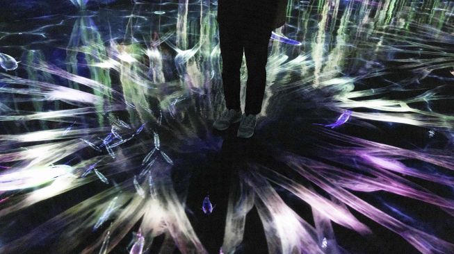 Seorang petugas berdiri di instalasi digital interaktif bernama "Catching and Collecting Forest" selama pratinjau media "teamLab Forest" di gedung hiburan BOSS E・ZO FUKUOKA, Fukuoka, Jepang, pada (16/7/2021). [Yuki IWAMURA / AFP]