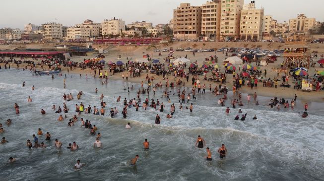 Foto udara warga berenang di Mediterania saat musim panas yang tinggi di Gaza, Palestina, pada (16/7/2021). [MOHAMMED ABED / AFP]