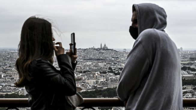 Pengunjung berfoto saat mengunjungi Menara Eiffel di Paris, Prancis, pada (16/7/2021). [Bertrand GUAY / AFP]