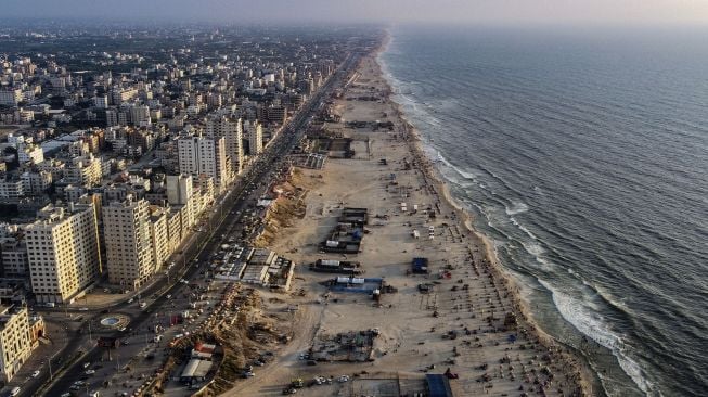 Foto udara menunjukkan sebagian pemandangan Kota Gaza dan warga Palestina berkumpul di sepanjang pantai saat musim panas yang tinggi di Palestina, pada (16/7/2021). [MOHAMMED ABED / AFP]