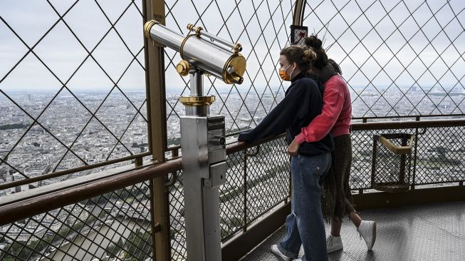 Pengunjung menikmati pemandangan dari lantai dua Menara Eiffel di Paris, Prancis, pada (16/7/2021). [Bertrand GUAY / AFP]