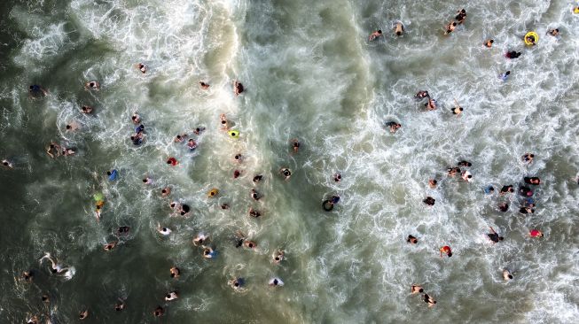 Foto udara warga berenang di Mediterania saat musim panas yang tinggi di Gaza, Palestina, pada (16/7/2021). [MOHAMMED ABED / AFP]