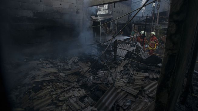 Petugas memadamkan sisa api yang membakar perkampungan padat penduduk di Jalan Lindung Pasar Baru, Teluk Gong, Jakarta Utara, Sabtu (17/7/2021). ANTARA FOTO/Aditya Pradana Putra