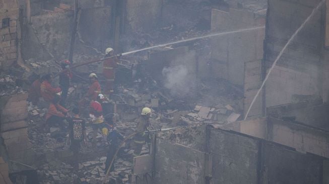 Petugas memadamkan sisa api yang membakar perkampungan padat penduduk di Jalan Lindung Pasar Baru, Teluk Gong, Jakarta Utara, Sabtu (17/7/2021). ANTARA FOTO/Aditya Pradana Putra